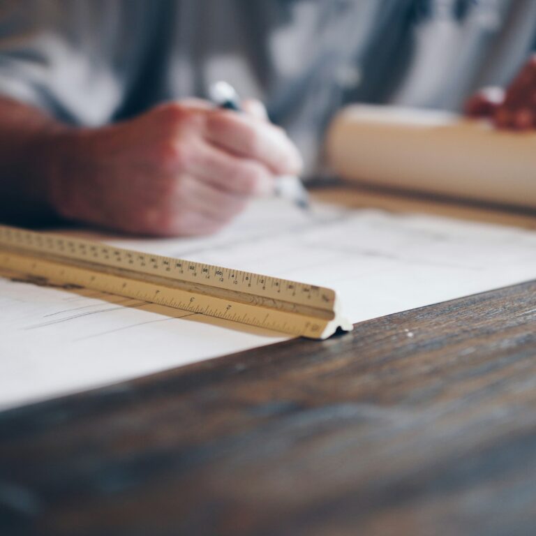 Architect hand-sketching blueprints with a ruler—traditional drafting before the rise of BIM.