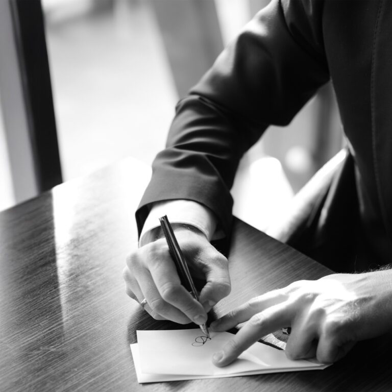 Close-up of a businessman writing with a pen on paper, symbolising creativity and architectural thought.